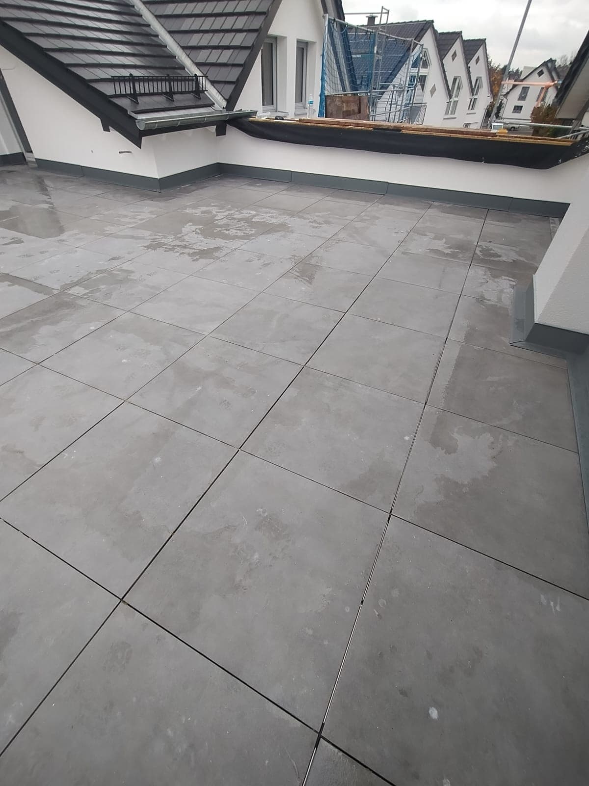 Dachterrasse mit großformatigem grauem Plattenbelag und sauberem Randabschluss